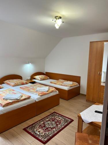 a bedroom with two beds and a table and a rug at PENSIUNEA KELEMEN in Praid