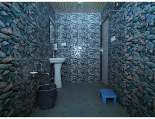 La salle de bains en pierre est pourvue d'un lavabo et d'un tabouret bleu. dans l'établissement Paradise kabins, srinager J&K, à Telbal