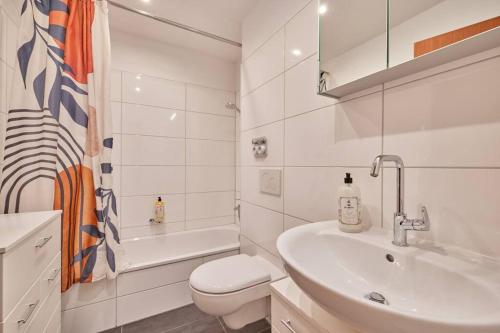 La salle de bains blanche est pourvue d'un lavabo et de toilettes. dans l'établissement *Design Studio nahe Frankfurt Bahnhof & Flughafen*, à Neulsenburg