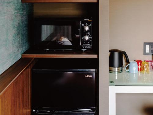 a microwave oven in a kitchen with a person taking a picture at Music Hotel Koza by Coldio Premium in Okinawa City