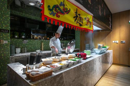 a chef standing in a kitchen preparing food at Hilton Garden Inn Ningbo in Ningbo