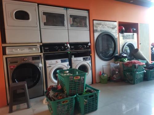 a laundry room with two washers and two drying racks at Autumn Living Hostel in Surabaya