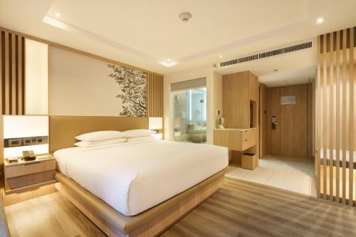 a bedroom with a large white bed and a bathroom at Courtyard by Marriott North Pattaya in Pattaya North