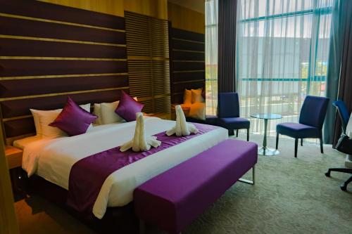 a bedroom with a large bed and chairs and a table at Greens Hotel & Suites in Bintulu