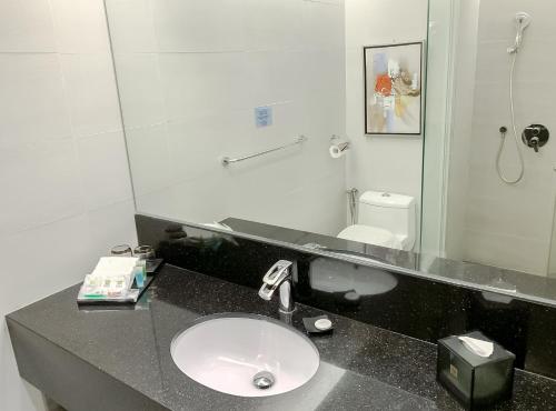 a bathroom with a sink and a mirror at Greens Hotel & Suites in Bintulu
