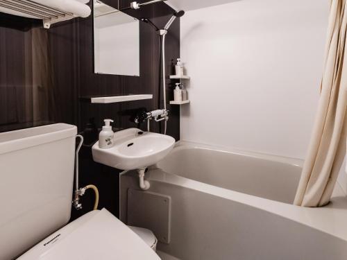 a bathroom with a toilet and a sink and a tub at Music Hotel Koza by Coldio Premium in Okinawa City