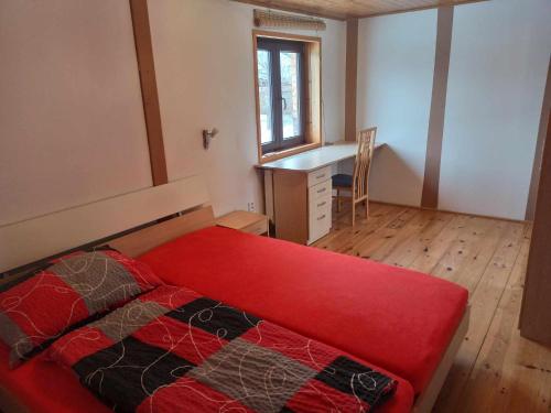 a bedroom with a red bed and a desk at Pavilon v ráji in Žďár