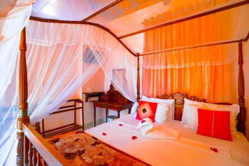 1 dormitorio con cama con dosel y almohadas rojas en Frangipani motel, en Galle