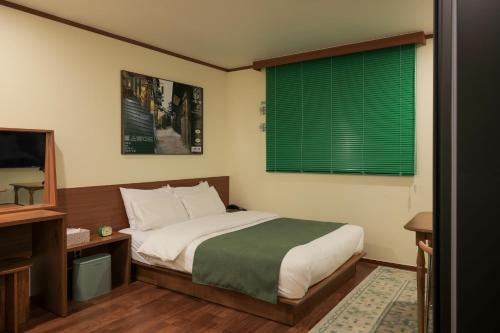 ein Schlafzimmer mit einem Bett und einem grünen Fenster in der Unterkunft Jeonju AANK Hotel in Jeonju