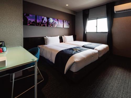 a hotel room with a large bed and a desk at Music Hotel Koza by Coldio Premium in Okinawa City