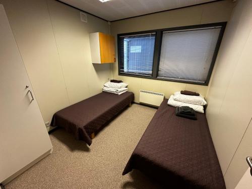 a small room with two beds and two windows at Nakvynes namelis in Norgėlai