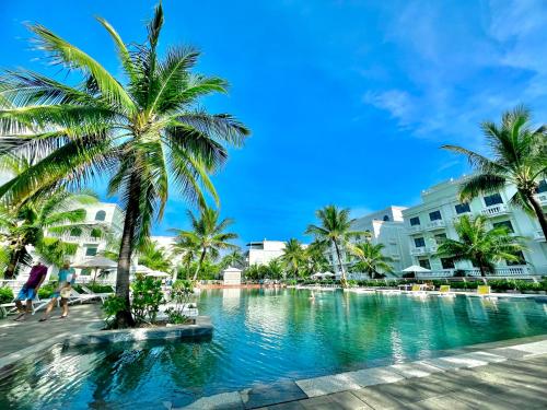 una piscina en un complejo con palmeras y edificios en Larosa Hotel en Phu Quoc