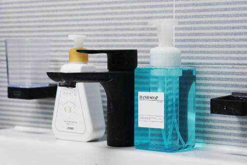a bathroom sink with two bottles of detergent and a sink at Pension Haneul Tari in Jeju