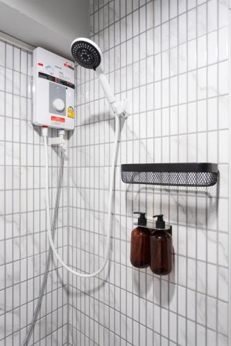 a white tiled wall with a shower head on a wall at A1 Duplex large room wt kitchen in Bangkok
