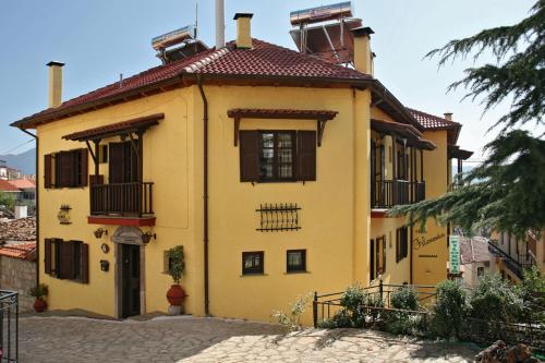 a yellow house with a red roof at Rigas Hotel Arachova in Arachova