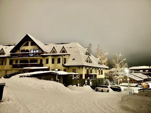 a snow covered building with cars parked in a parking lot at APARTMÁN MEZONET DONOVALY Plesnivec in Donovaly