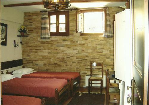 a bedroom with two beds and a brick wall at Rigas Hotel Arachova in Arachova