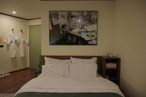 a bedroom with a bed with white sheets and a picture on the wall at Aank Hotel Jeonju in Jeonju
