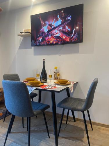 a dining room table with chairs and a tv on the wall at Apartment & Studio Forest Paradise in Cerkno