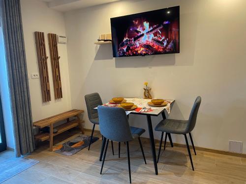 a dining room with a table with chairs and a tv on the wall at Apartment & Studio Forest Paradise in Cerkno
