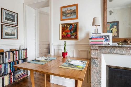 - un salon avec une table en bois et une cheminée dans l'établissement Appartement Mélèze - Welkeys, à Paris