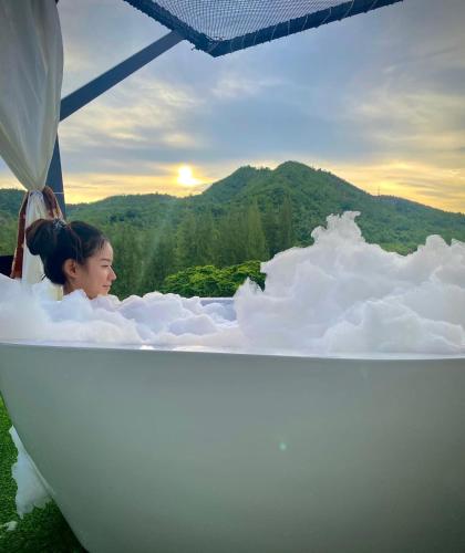 a young girl sitting in a bath tub with a view at เคียงดาว โฮมสเตย์ แก่งกระจาน in Ban Song Phi Nong