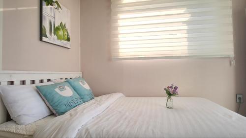 a bedroom with a bed with a vase of flowers on it at Pension Haneul Tari in Jeju