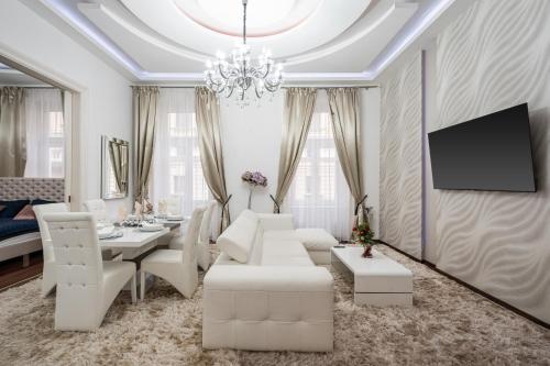a living room with white furniture and a chandelier at Opera Balkony Luxury Apartment in Budapest