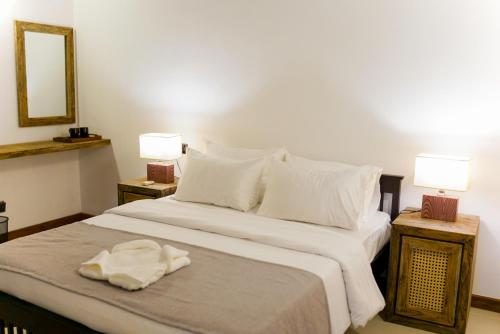 a bedroom with a bed with white sheets and two lamps at Chariot Square in Kandy