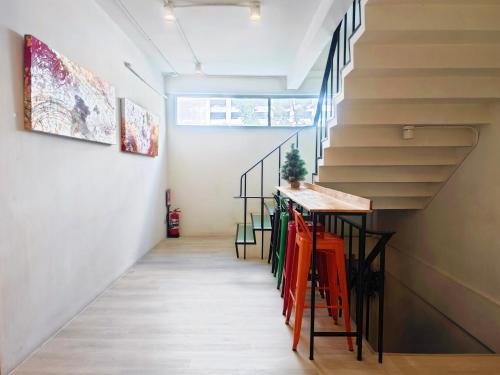 a hallway with a staircase with orange stools at Ostay Asoke Bangkok in Makkasan