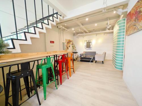a bar with colorful stools in a room with stairs at Ostay Asoke Bangkok in Makkasan
