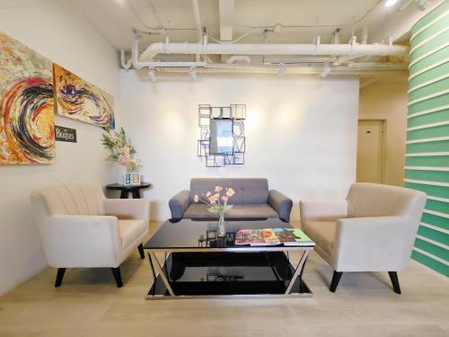 a living room with a couch and two chairs and a table at Ostay Asoke Bangkok in Makkasan