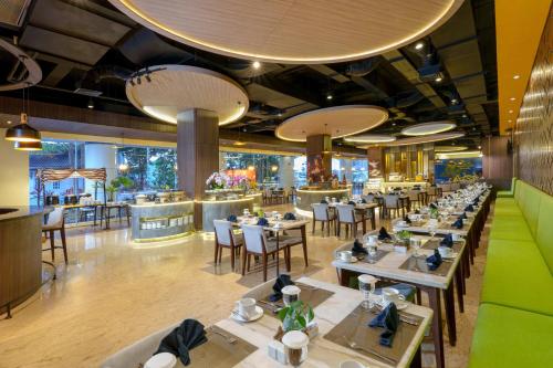 un restaurante con mesas y sillas y un bar en Golden Tulip Springhill Lampung en Bandar Lampung