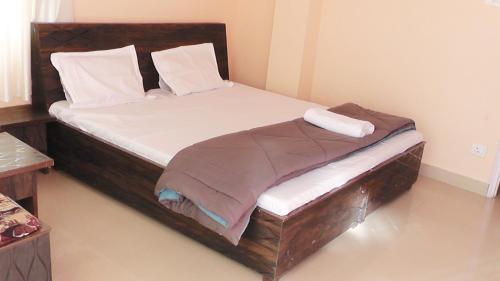 ein Schlafzimmer mit einem großen Bett mit einem Holzrahmen in der Unterkunft Lakshay Regency in Shimla
