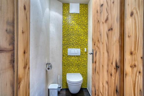 a bathroom with a toilet and a yellow wall at Appartement Hofmann in Königsleiten