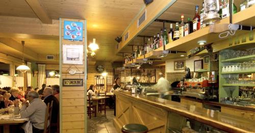 a group of people sitting at a bar in a restaurant at La Locanda in Livigno