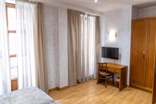 a bedroom with a desk with a television and a bed at Hotel Granada Centro in Granada