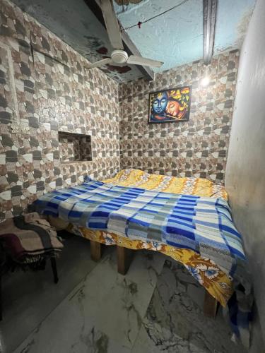 a bedroom with a bed with a blue and yellow quilt at Shyam Sadan Guest House in Vrindāvan
