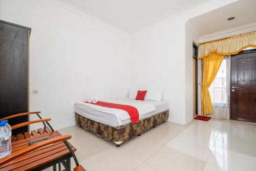 een witte slaapkamer met een bed en een raam bij Grha Rahadi 2 Wiyung RedPartner in Surabaya