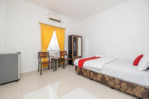 a bedroom with two beds and a table and chairs at RedDoorz at Gunungsari Surabaya 2 in Surabaya
