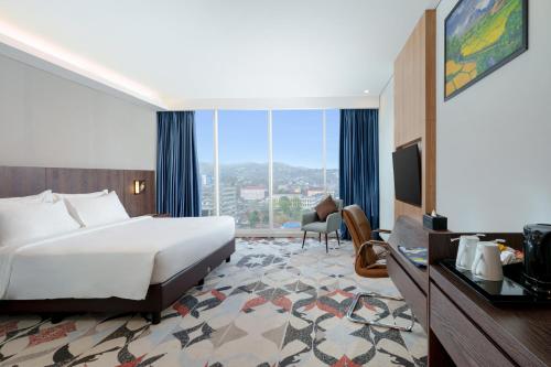 a hotel room with a bed and a large window at Golden Tulip Springhill Lampung in Bandar Lampung