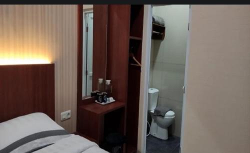 a bedroom with a bed and a bathroom with a toilet at J&L Inn Semarang in Semarang