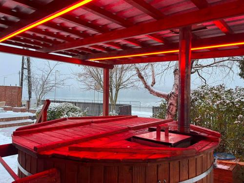a wooden deck with a hot tub under a pergola at Volenter Lux Duna Spa in Baja