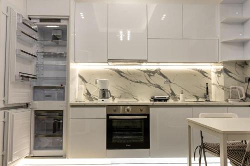 a white kitchen with white cabinets and a table at The Golden home 1 in Piraeus