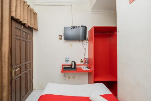 Cette chambre comprend un lit, une armoire rouge et une télévision. dans l'établissement RedDoorz Plus @ Gunungsari Surabaya, à Kedurus