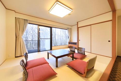 a living room with a table and chairs and a large window at FOURTREAT plus NASUKOGEN in Nasu