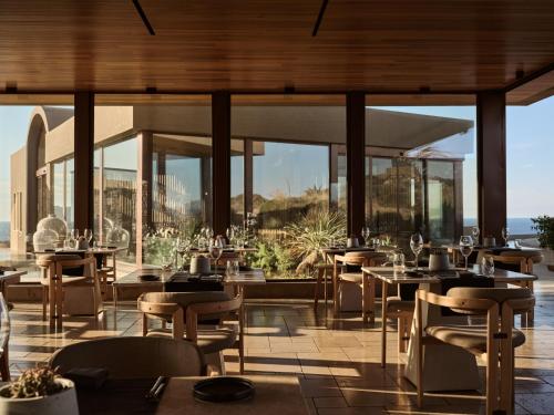 a restaurant with tables and chairs and windows at Acro Suites - A Wellbeing Resort in Agia Pelagia