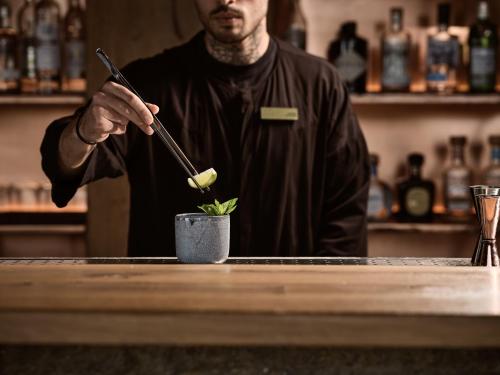 a man standing behind a bar holding at Acro Suites - A Wellbeing Resort in Agia Pelagia