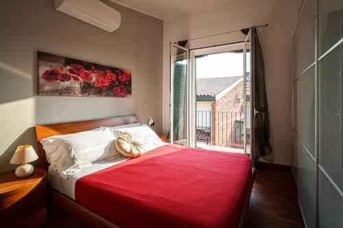 a bedroom with a bed with a red blanket and a window at Accomodo MIT39 Trivano San Siro in Milan