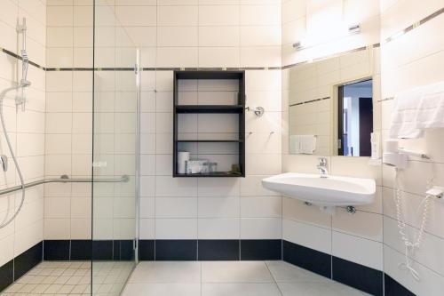 a bathroom with a sink and a glass shower at eduCARE Hotel in Treffen